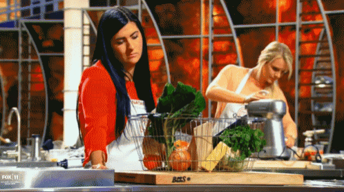 two women are preparing food in a kitchen with a cutting board that says aces