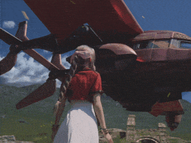 a woman in a red shirt and white skirt is standing in front of a giant robot