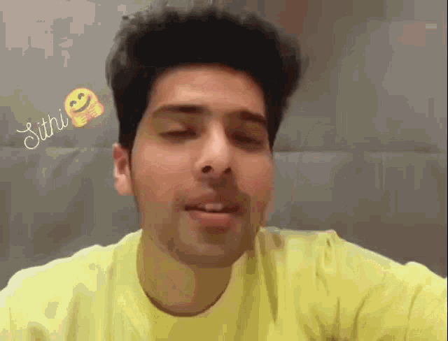 a man in a yellow shirt is smiling with a smiley face behind him that says sitri