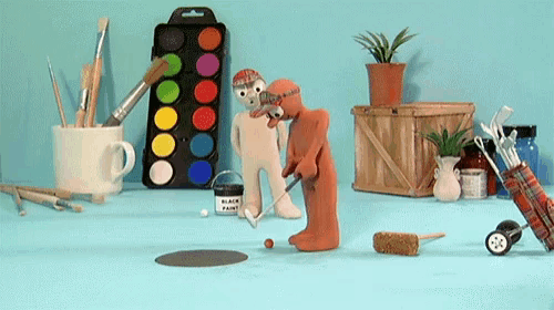 a bucket of black paint sits on a table next to a figurine of a man playing golf
