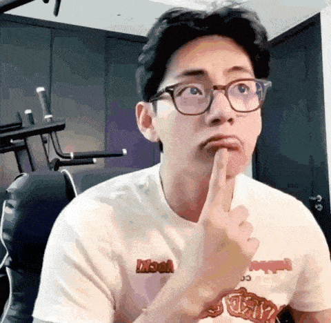 a man wearing glasses and a white t-shirt is making a funny face .