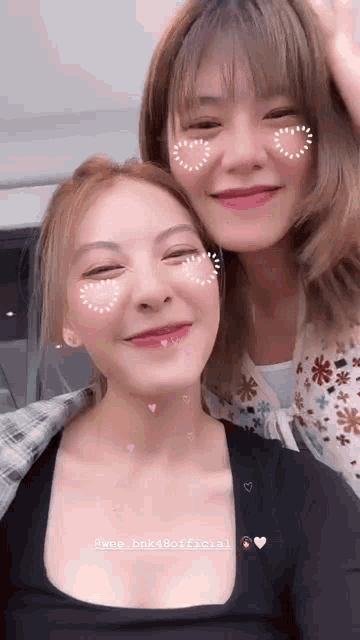 two girls are posing for a picture together and smiling .