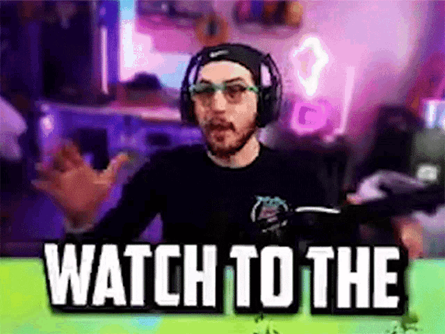 a man wearing headphones and glasses is sitting in front of a screen that says watch to the