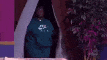 a man wearing a green nike hoodie is standing in a doorway .