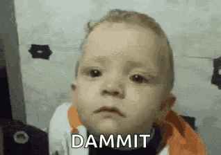 a baby is making a funny face and says dammit .