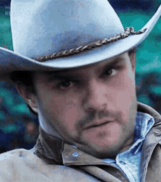 a man wearing a cowboy hat and a jacket is making a funny face .