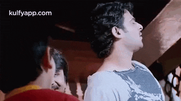 a group of men are standing next to each other in a room and one of them is looking up at the sky .