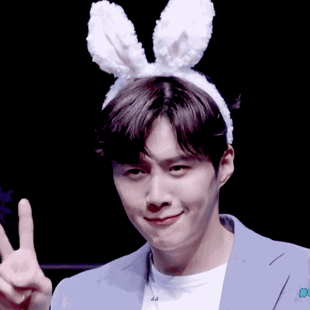 a man wearing bunny ears and a blue suit giving a peace sign