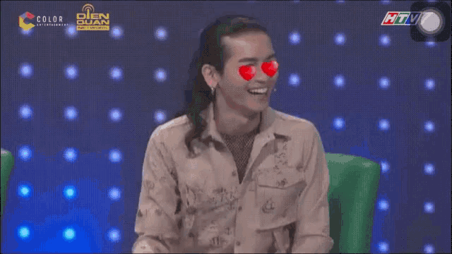 a man with heart shaped eyes is sitting in front of a screen that says htv