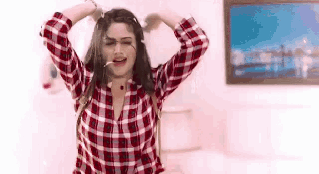 a woman in a plaid shirt is standing in a room with her arms outstretched .