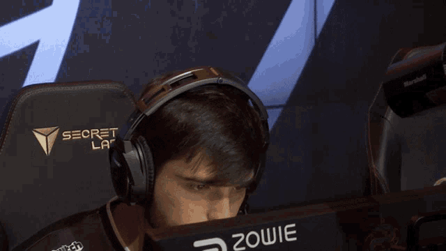 a man wearing headphones sits in a chair that says secret