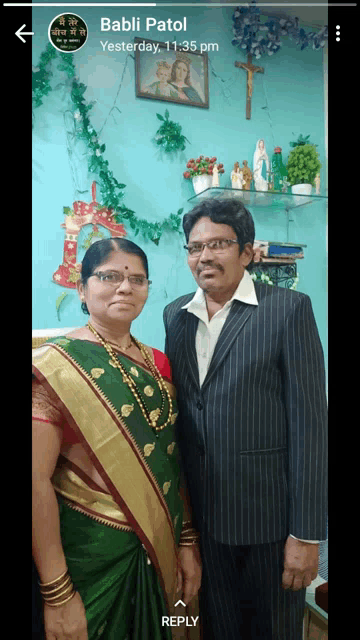 a man and a woman are posing for a picture in front of a wall with a picture of jesus and mary on it