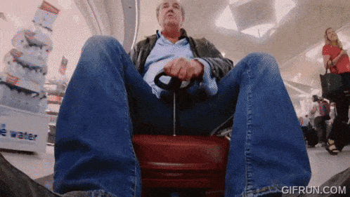 a man is sitting on a suitcase in front of a sign that says " e water "