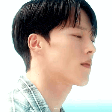 a close up of a man 's face with a plaid shirt on