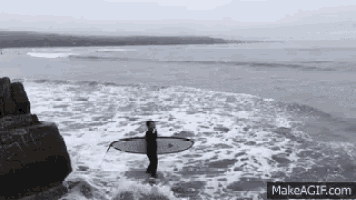 a man is carrying a surfboard in the water .