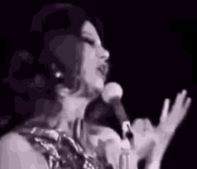 a woman is singing into a microphone on a stage .