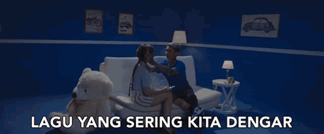 a man and a woman are sitting on a couch with a teddy bear and the words lagu yang sering kita dengar above them