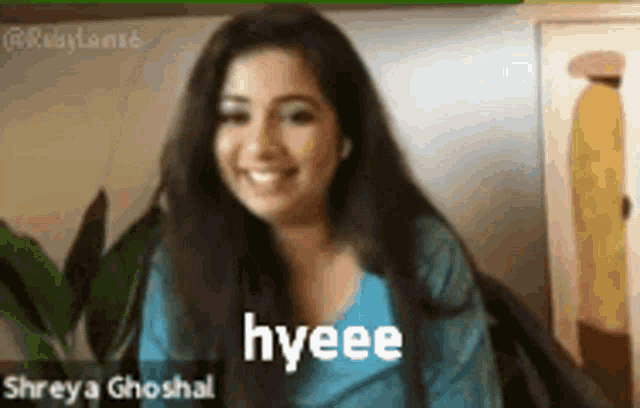 a woman in a blue shirt is smiling with the word hyeee on her face