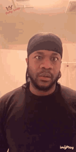 a man wearing a black shirt and a black headband with the word belly boop on the ceiling