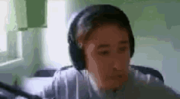 a man wearing headphones is sitting in front of a microphone .