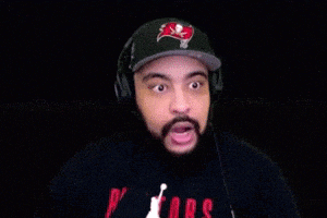 a man with a beard is wearing headphones and a hat with a buccaneers logo on it .