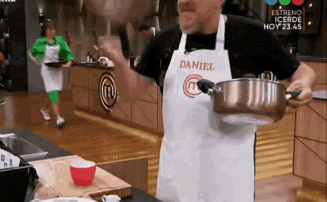 a man wearing an apron with the name daniel on it is holding a pot