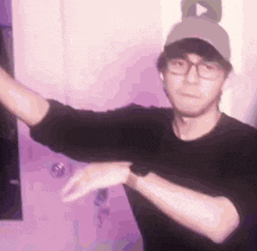 a man wearing glasses and a baseball cap is dancing in front of a door .