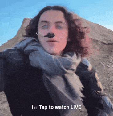a video of a man with long hair says tap to watch live at the bottom