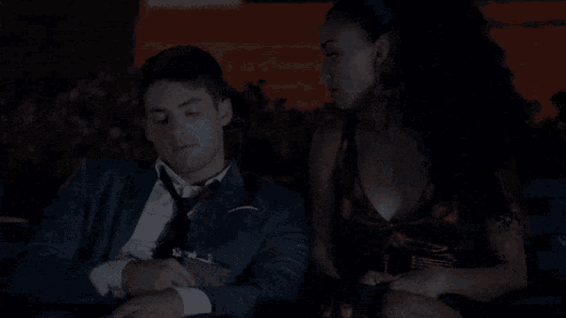 a man in a suit and tie is sitting next to a woman in a red dress .