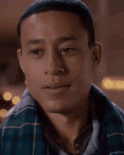 a man wearing a plaid shirt and a scarf is smiling