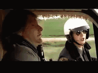 a man wearing a helmet and sunglasses is talking to another man wearing a helmet .