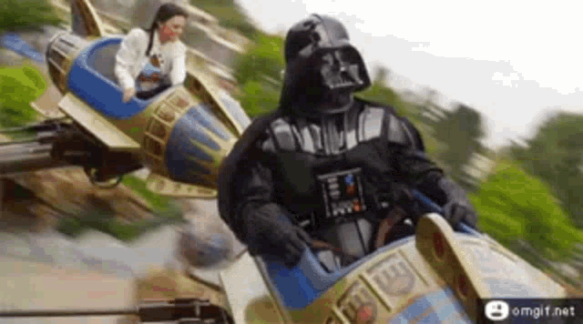 a man dressed as darth vader is riding a roller coaster with a woman .