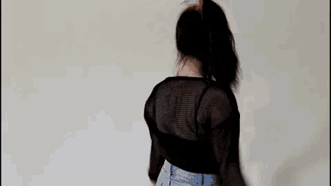a woman is dancing in a black shirt and blue jeans .
