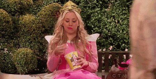 a woman dressed as a princess is sitting on a bench eating chips .