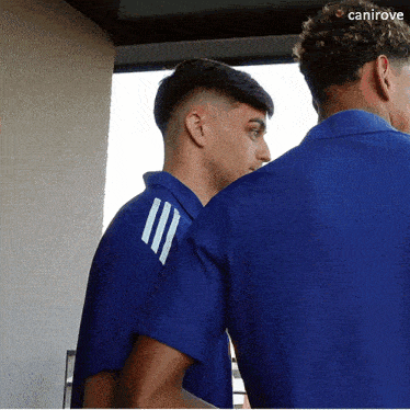 two men in blue shirts are standing next to each other and the word canirove is on the bottom