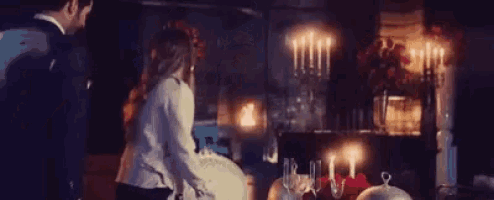 a man and a woman are standing in front of a table with candles on it .