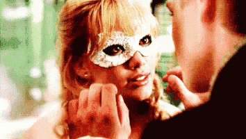 a man is touching a woman 's face who is wearing a mask .