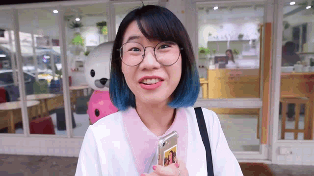 a woman with blue hair is holding a cell phone