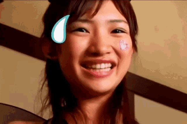 a close up of a woman with a sticker on her face smiling .