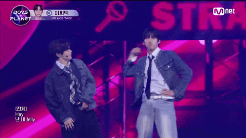 a group of young men are dancing on a stage in front of a sign that says mnet