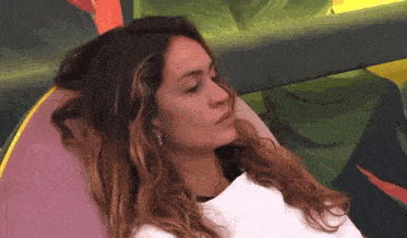 a woman with long hair is laying in a chair with a painting in the background