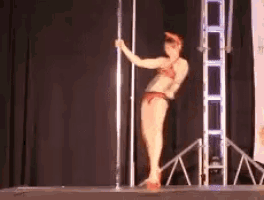 a woman in a bikini is standing on a pole on a stage