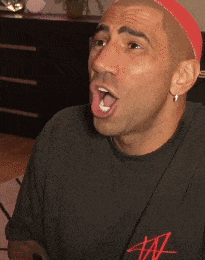 a man wearing a black shirt with the letter a on it is sticking his tongue out