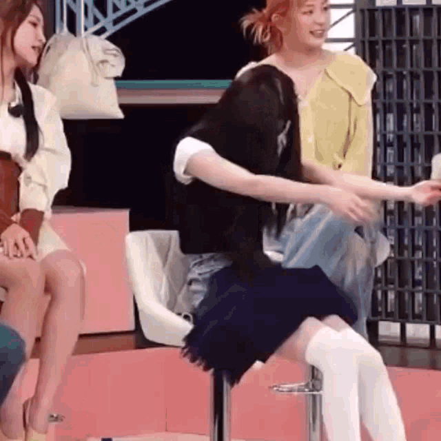 a woman is sitting on a chair with her legs crossed and a woman is sitting next to her .