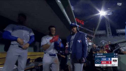 a man in a blue jays uniform is standing in the dugout