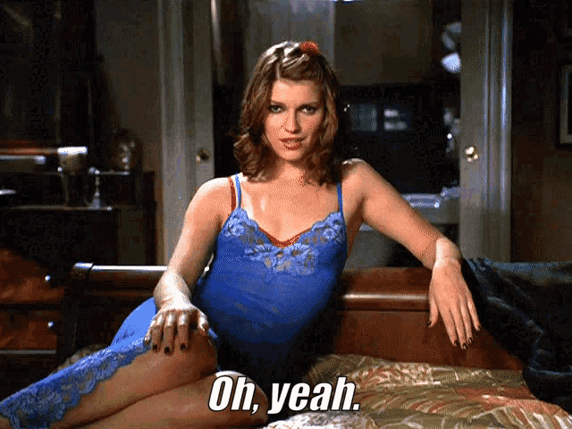 a woman in a blue lace dress is laying on a bed with the words oh yeah below her