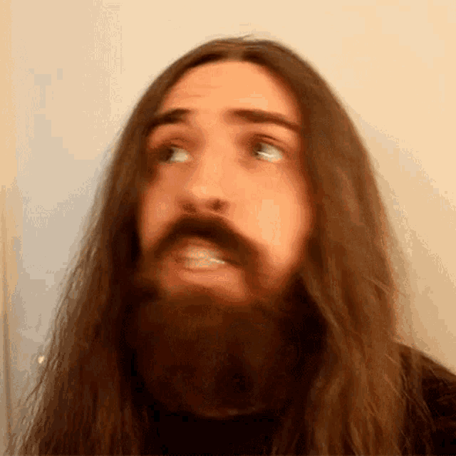 a man with long hair and a beard making a face
