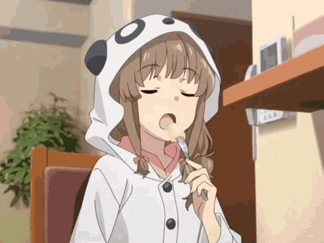 a girl wearing a panda hooded jacket is eating something