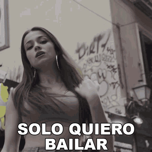 a woman stands in front of a wall that says solo quiero bailar on it