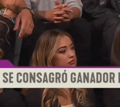 a woman is sitting in front of a sign that says `` se consagro ganador '' .